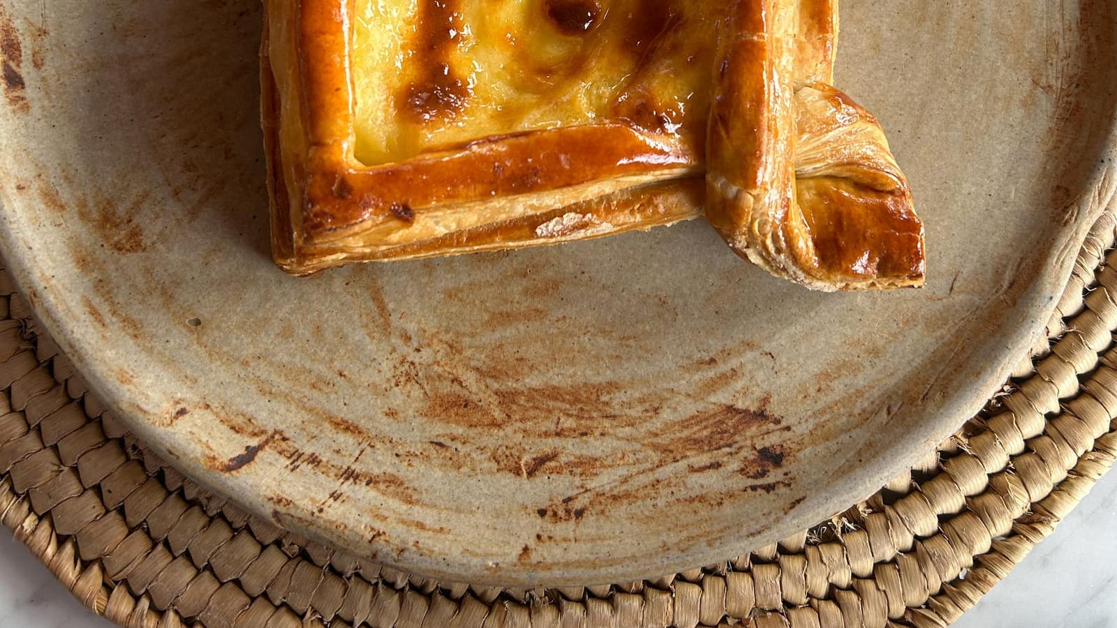A square custard pastry with a golden caramelized top dusted with powdered sugar.