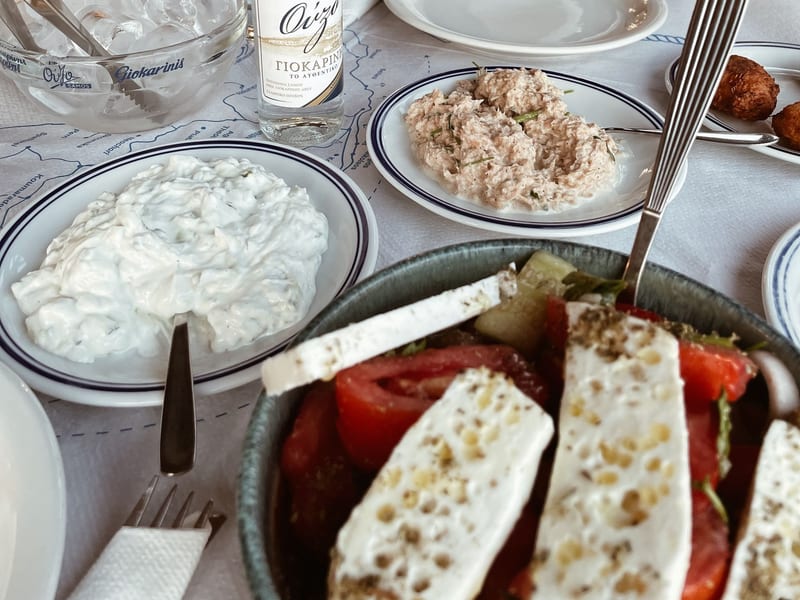 A Cretan taverna table set with dakos, tzatziki, feta, and ouzo.