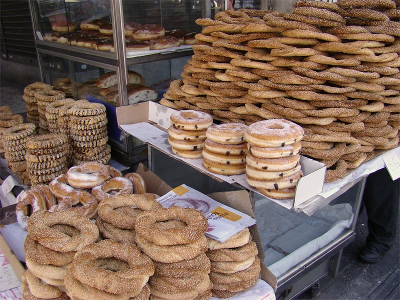 Large stacks of sesame koulouri rings piled high at an Athens street vendor's cart.
