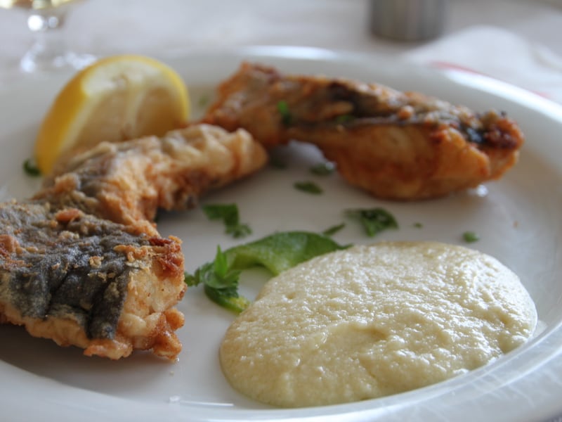 Fried cod fillets served with a side of skordalia and a lemon wedge, a classic Greek pairing.