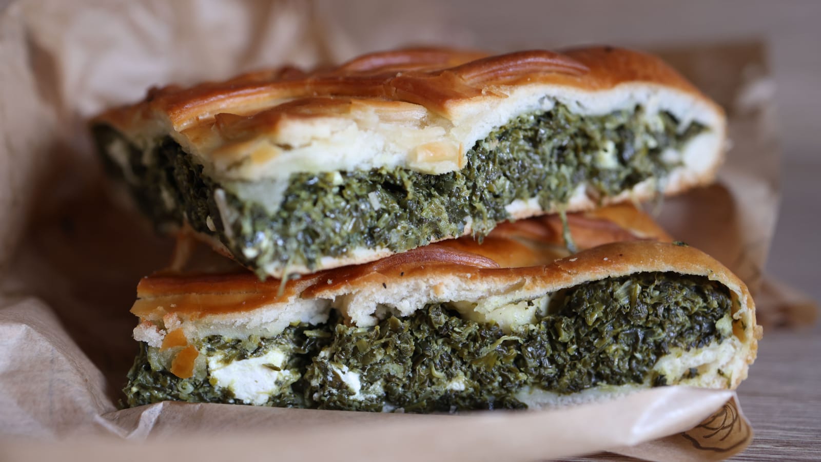 Cross-section of baked spanakopita showing the green spinach and feta filling inside a golden pastry crust.